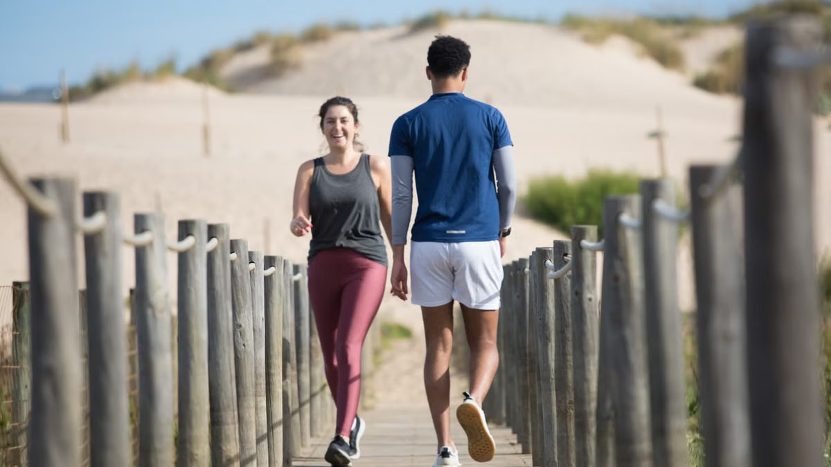 A couple enjoys jogging on a sunny beach boardwalk in Portugal, capturing a moment of fitness and leisure.