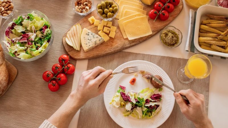 Overhead view of a cheese platter with fresh salad and juice, perfect for a gourmet lunch setting.